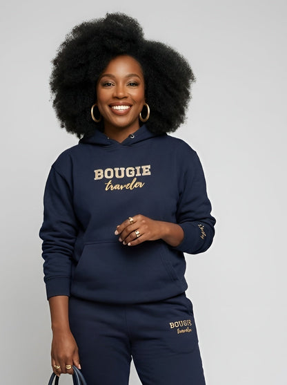 Woman wearing a navy tracksuit with 'BOUGIE' text, holding a matching handbag on a gray background