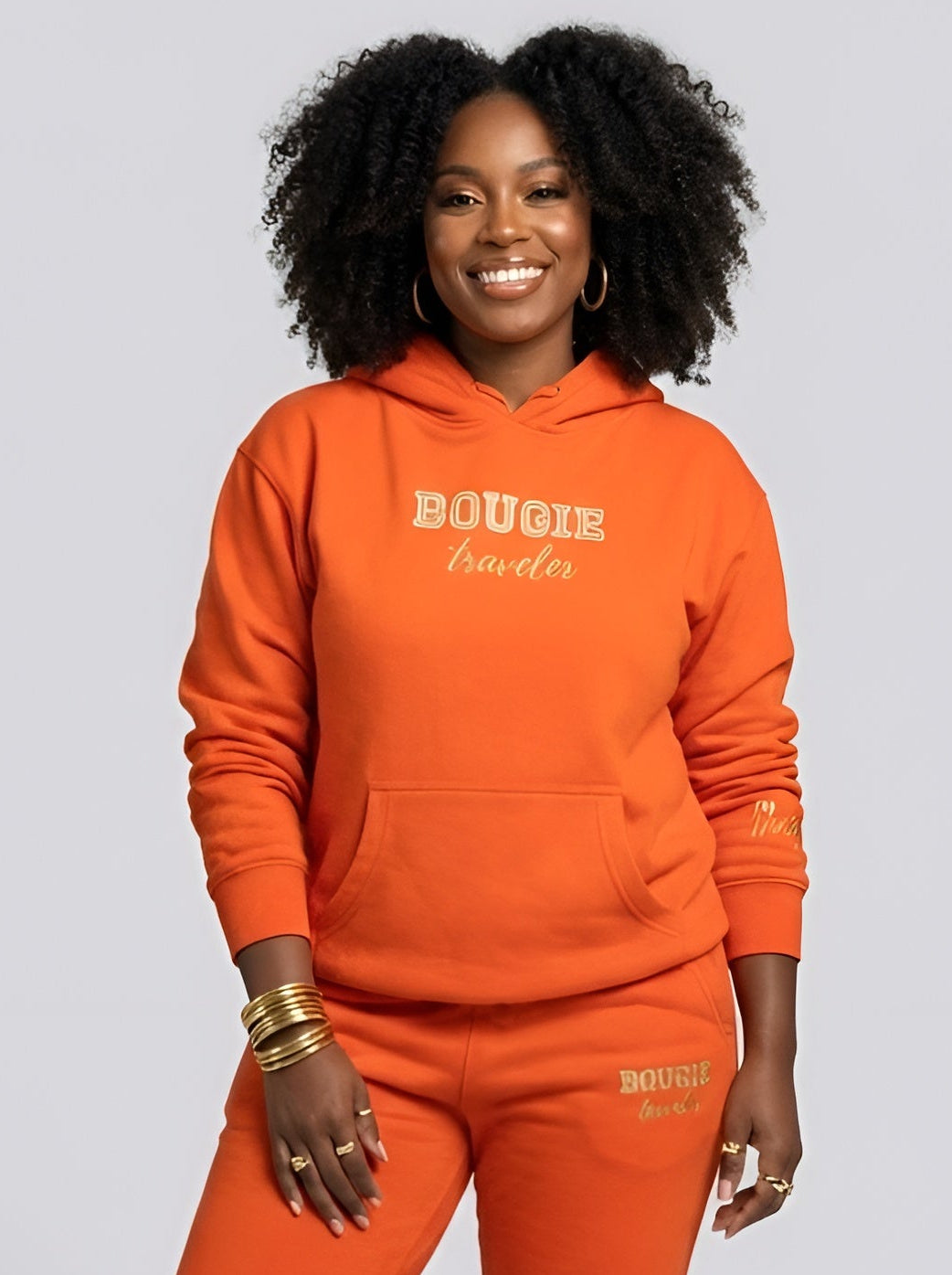 Person wearing an orange tracksuit with 'BOUGIE' branding on a light gray background