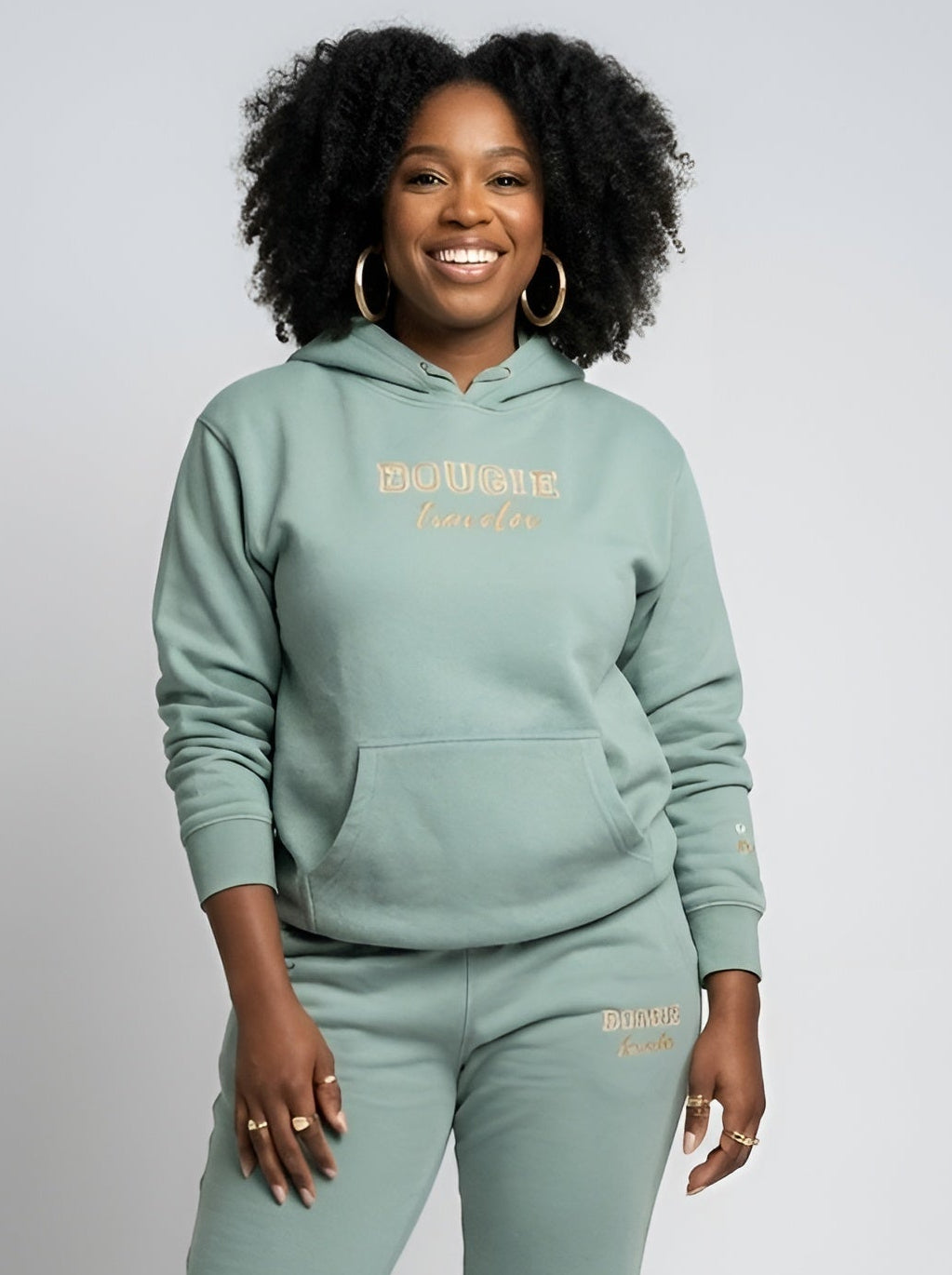 Person wearing a matching green hoodie and jogger set on a white background