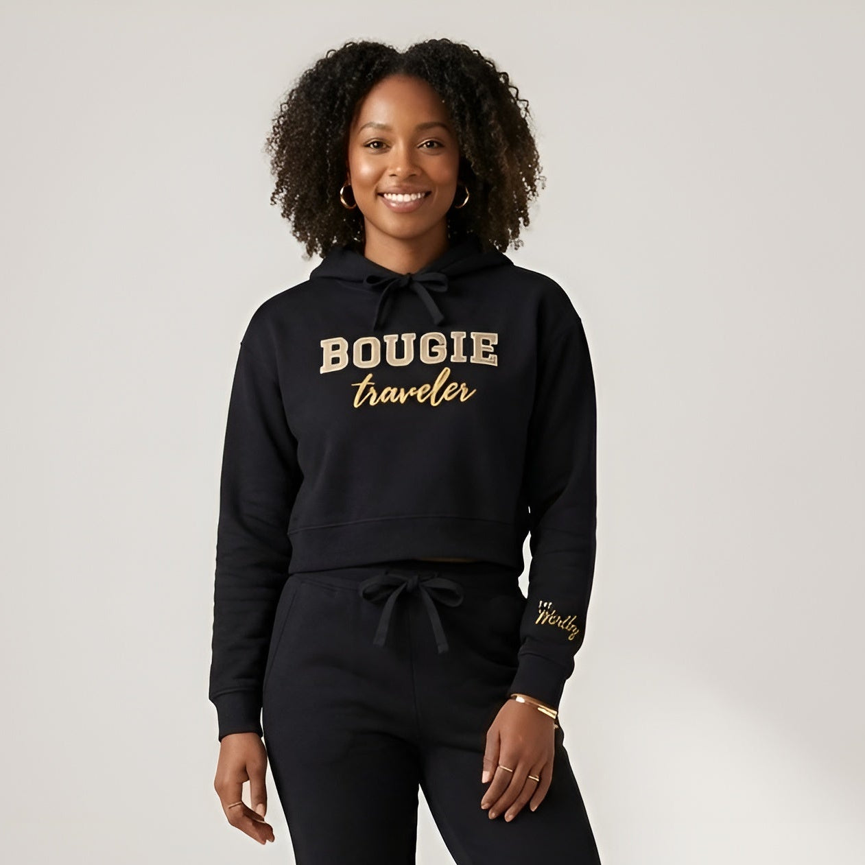 Woman wearing a black hoodie with 'BOUGIE traveler' text on a white background